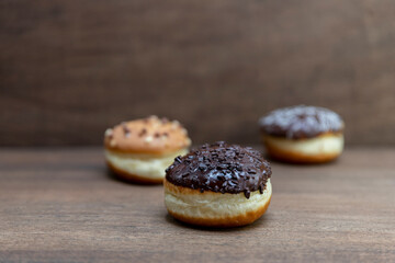 Delicious glazed chocolate donuts on wooden background
