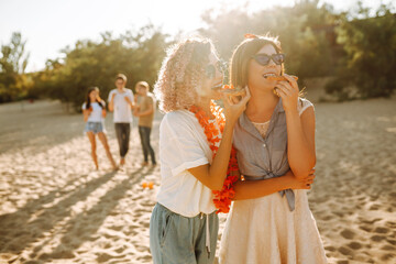 Happy young friends having fun on the beach and eating pizza. Fast food concept. Nature,  summer vacation, Beach holiday,  relax and lifestyle.