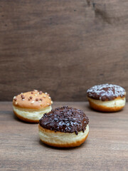 Delicious glazed chocolate donuts on wooden background