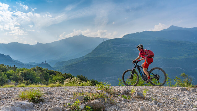 nice, active  senior woman riding her electric mountain bike in the huge rock fall area of Marocche di Dro, in the Sarca Valley, Garda lake mountains, Trentino, Italy 
