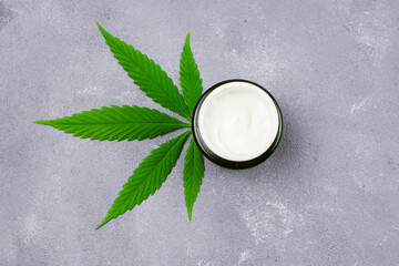 CBD moisturizer cream with marijuana leaf - cosmetic cannabis concept. Flat lay, top view. Jar with...