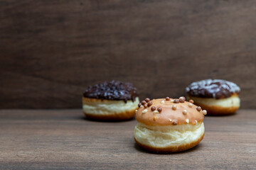 Delicious glazed chocolate donuts on wooden background