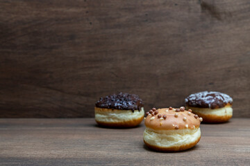 Delicious glazed chocolate donuts on wooden background