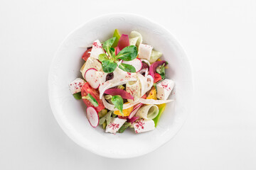 Salad with tomatoes, corn, radishes and feta cheese in white bowl isolated on white background
