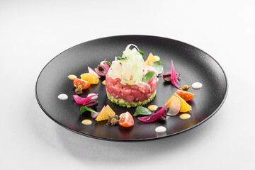 Tuna tartar garnished with orange, tomatoes and olives isolated on white background