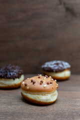 Delicious glazed chocolate donuts on wooden background
