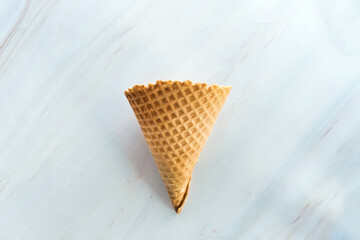 Empty ice cream waffle cone on marble background. Blank wheat wafer cone for an ice-cream