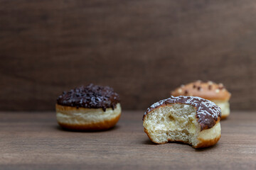 Delicious glazed chocolate donuts on wooden background
