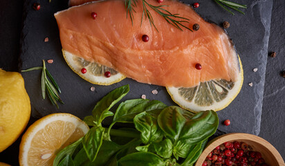 Fresh fish. piece of raw salmon fish fillet, spices on a black stone surface, Delicious fish meat. top view. Healthy food.