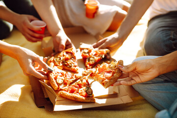 Obraz na płótnie Canvas Hands taking slices of pizza close view. Group of Friends eating pizza at the beach. Fast food concept. Picnic at the beach. Summer vacation, holidays, travel, lifestyle and people concept.