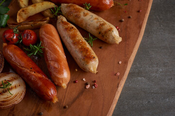 sausages and ingredients for cooking. Grilled sausage with the addition of herbs and and spices, vegetables, rosemary, thyme on the grill plate, Grilling food, bbq, barbecue, on stone table. Top view.