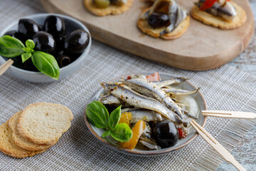 anchovy appetizer with olives. Mediterranean appetizer, anchovy fish in olive oil and herbs in a small bowl.