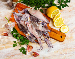 Fototapeta na wymiar Seafood delicacy, heap of fresh white calamari on wooden cutting board