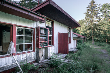 Old abandoned wooden house falling apart. Broken windows, scattered glass, white walls, red doors...