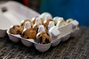 packaging with fresh quail eggs in different colors from the side