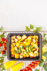 The concept of a vegetarian picnic and healthy food. Vertical, healthy, food composition with a baking tray with farm, young potatoes, berries and seasonal vegetables on a grill with copy space