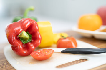 Red bell sweet pepper and tomato with knife on cutting board, vegetable salad, cooking healthy food