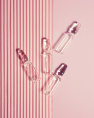 many medical ampoules on a pink background, vaccination and treatment