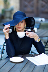Exquisite woman in a black hat drinks coffee - 440806272