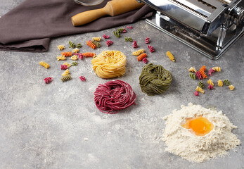 Tagliolini pasta raw, multicolored, Italian dish, on a gray table top view, horizontal,  no people,