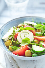 Summer Salad with Cream Cheese, green Olives, Tomatoes and fresh Basil. Bright wooden background. Close up. 