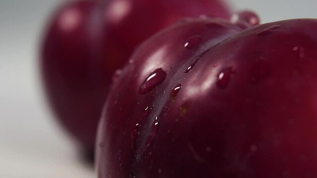 Fresh plums with water drops. Flowing and splashing in slow motion. Sprinkling and washing fruit
