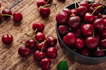 Closeup shot of fresh red cherries on a bowl on a wooden table