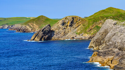 Fototapeta premium Rock cliffs jutting into the blue sea in the Cantabrian Sea. Santander.