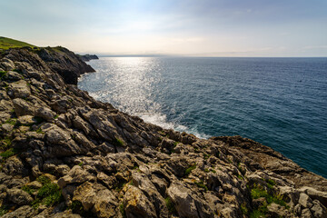 Fototapeta na wymiar Sun setting on the sea horizon with stone cliffs.