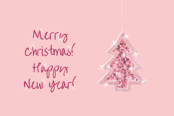 Obraz na płótnie Canvas Winter celebration concept with hanging pink sparkling Christmas tree toy, minimal greeting card