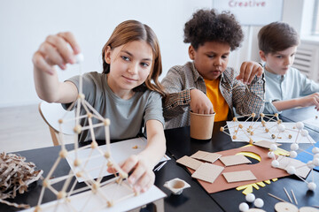 Diverse group of children making wooden models during art and craft class in school, copy space