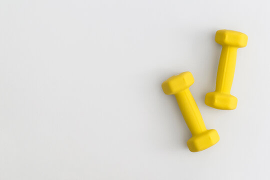 Pair of yellow dumbbells on white background