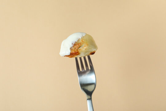 Fork with varenik or pierog on beige background
