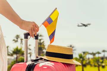 Woman with pink suitcase and Colombia flag standing on passengers ladder and getting out of...