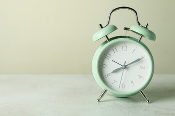 Stylish mint alarm clock against beige background