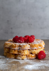 Three waffles stacked, garnished with raspberries, vertical