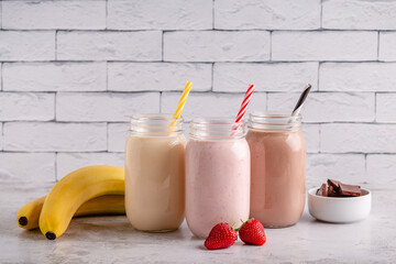 Set of strawberry banana and chocolate milkshakes in glass jars
