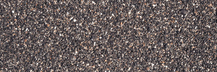 Abstract background with black and orange round sea pebble stones texture on the shore close up in...
