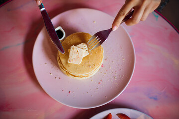 Portion of buttered pancakes on round pink plate. Concept of taste and enjoyment. Homemade food. Recreation and travel. National cuisine. Proper nutrition. Carefree summer.