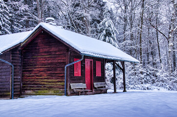 Schneebedeckte rote Waldhütte im Winter