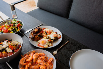 Cooked scrambled eggs with salad. Shakshuka serving on the summer terrace. Breakfast outside. Fried eggs on the summer terrace for breakfast. Breakfast is served on the table for two. Food day. Greek 