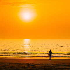 Fototapeta premium Silhouette Of Young Caucasian Lady Woman In Swimsuit Walking In Sea Beach During Sunset. Vacation On Ocean Beach. Sundown Above Sea Horizon At Sunset. Natural Sunrise Sky Warm Colors Over Ocean