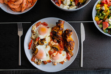 Cooked scrambled eggs with salad. Shakshuka serving on the summer terrace. Breakfast outside. Fried...