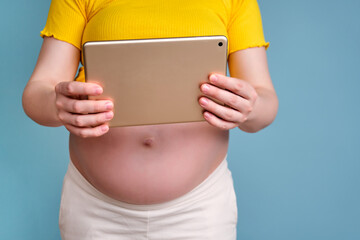 A pregnant woman holds a tablet in her hand for shooting videos and photos