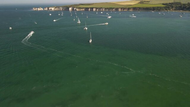Drone footage flying over clear waters of the sea with boats and yachts, sailboats on a hot summer holiday