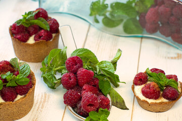 Delicious mini tartlet pies with ripe raspberries and mint, cheese custard cream filling and cold...