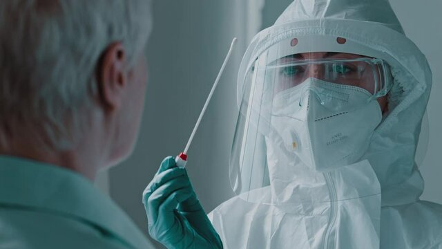 Portrait scientist in laboratory doctor nurse woman wearing medical protective uniform clothing using equipment for doing coronavirus swab Covid-19 pcr test to female old lady patient during pandemic