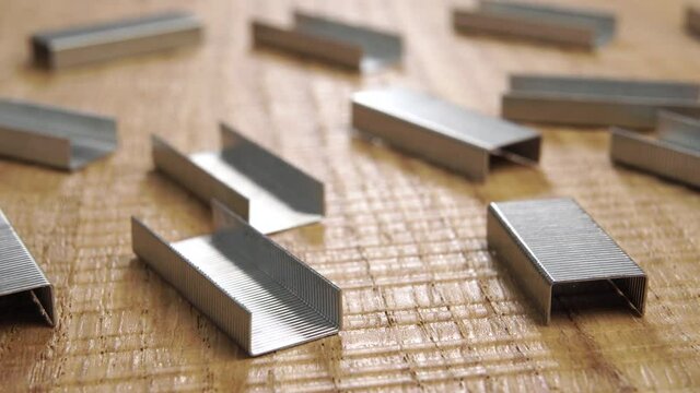 Stapler staples on a detailed wooden surface. Office accessories and repair tools. Macro. Dolly shot