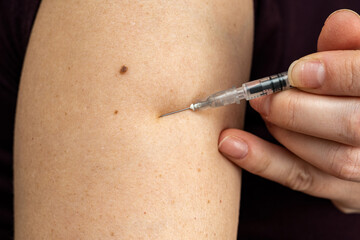 Injection of insulin into shoulder of woman from syringe