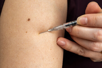Injection of insulin into shoulder of woman from syringe